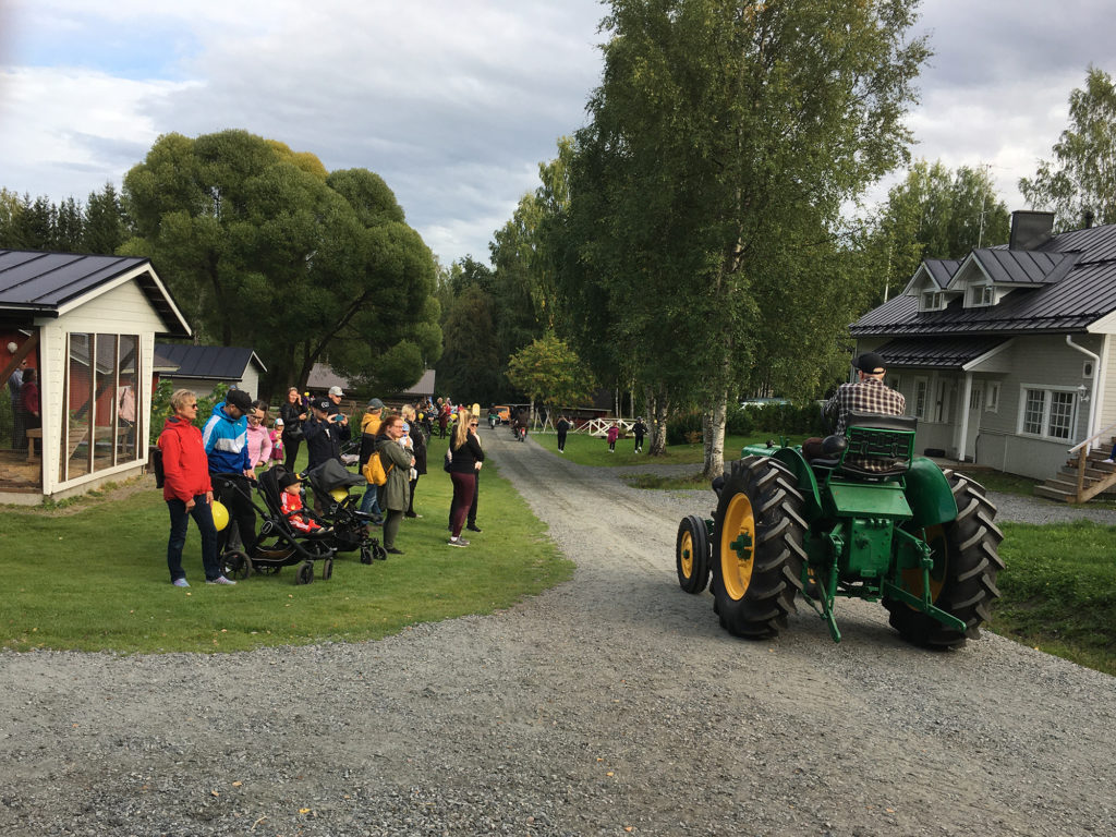 Yleisöjoukko ihmettelemässä traktorin ohiajoa.