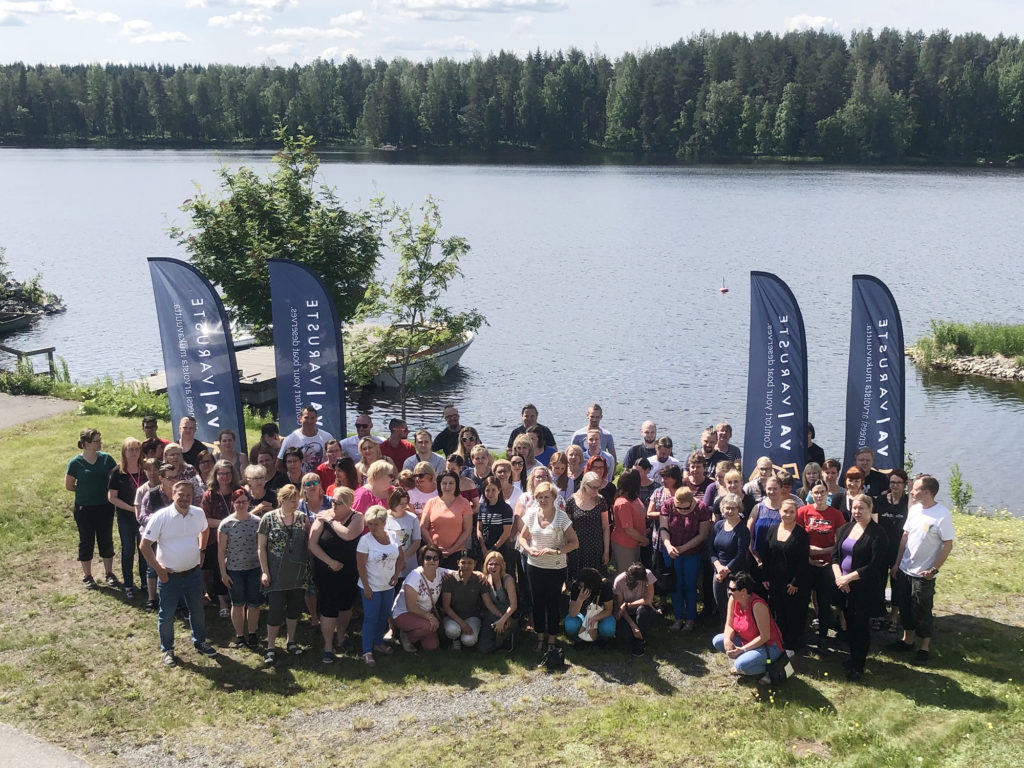 ryhmäkuva kymmenistä henkilöistä kesällä veden äärellä